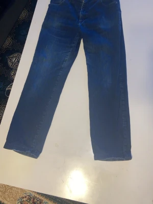 Blå raka jeans från Westis båda för 400kr - Säljer ett par klassiska blå jeans från Westis med rak passform. Jeansen är tillverkade i Italien och består av 98% bomull och 2% elastan för lite stretch. Perfekta för dig som gillar en tidlös look och bekväm känsla.