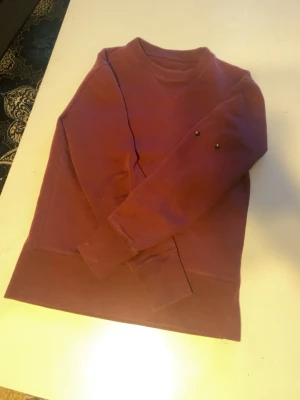 Två vinröda hoodies utan tryck - Säljer två stilrena vinröda hoodies i mjukt bomullsmaterial. Ena modellen har huva med dragsko och magficka, den andra är utan huva och har minimalistisk look med små metallknappar på ärmen. Perfekta för en chill och avslappnad stil.