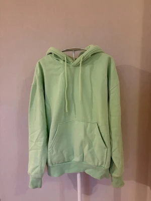 Pastellgrön hoodie - Säljer en pastellgrön hoodie från Weekday i storlek XS. Hoodien har en stor magficka framtill och ribbade muddar vid ärmslut och nederkant. 