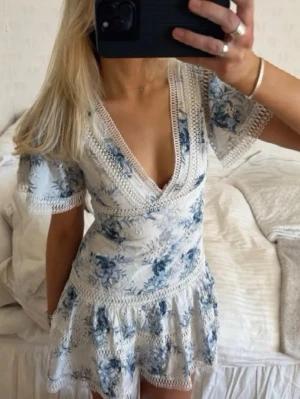 Blommig kortklänning med spetsdetaljer - Säljer denna sååå perfekta klänningen i så bra kvalitet. Superbra skick och så smickrande och  fin passform💕 perfekt att ha i sommar på tex studentmottagningar!! Se mått! Midja rakt över: ca 38cm, höfter rakt över: ca 45, byst rakt över: ca39cm, längd: ca 83cm. De två sista bilderna är mina🌸