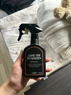 Lush I Love You To Peaches Body Spray 🍑🍬 - Fräsch body spray från Lush i doften I Love You To Peaches. Kommer i en svart sprayflaska på 200 ml med persikotoner, vildapelsin och passionsfrukt. Flaskan har en modern, stilren design med rosa detaljer och tydlig etikett. Oanvänd! 