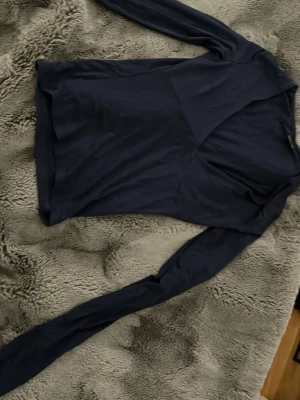 Marinblå långärmad topp - Snygg marinblå långärmad topp med v-ringad skärning framtill. Tunn och mjuk i materialet, perfekt att styla med jeans eller kjol. Enkel design utan mönster eller detaljer, vilket gör den lätt att matcha.
