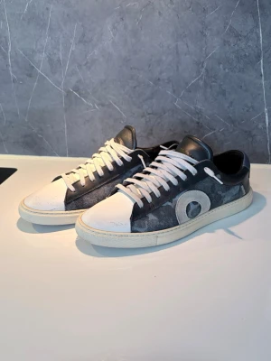 Oliver Cabell Low 1’s  - Ett par riktigt schyssta, stilrena, Oliver Cabell low 1’s med camo på sidan. Oerhört snygga, i bra skick endast med lite crease och en liten skavank bak vid hälen, därmed priset.                                    Passa på, riktigt fet deal! Säljer pga att storleken ej passade bra.                                                             - Storlek: 40, kan passa med 41.                               - Paket lämnas alltid in inom 24h efter beställning, alltid!