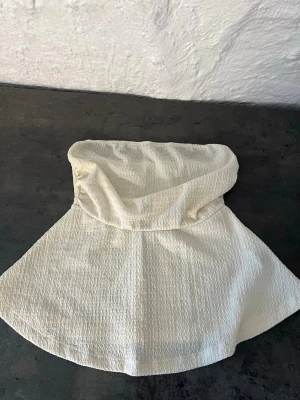 Krämvit strukturerad sjal - Säljer en krämvit sjal i strukturerat tyg. Sjalen har en mjuk och lätt känsla med en enkel, stilren design. Perfekt att slänga över axlarna för en extra touch till din outfit.