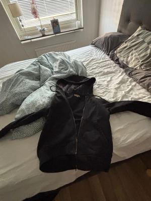 Svart zip-hoodie från Burberry - Svart hoodie från Burberry med dragkedja framtill och klassisk huva. Stilsäker och enkel design med fickor på sidorna och justerbara snören i huvan. Perfekt för dig som gillar exklusiva streetwear-vibbar och vill ha något från ett ikoniskt märke. Satte priset högt så nu kan buda 