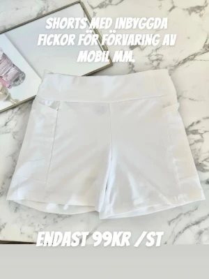 Vita shorts med fickor- student  - Snygga vita shorts med inbyggda fickor perfekta för mobilen eller andra småsaker. De har en bred midja och är tillverkade i ett stretchigt material som ger en bekväm passform. Perfekta till under studentklänningen! 