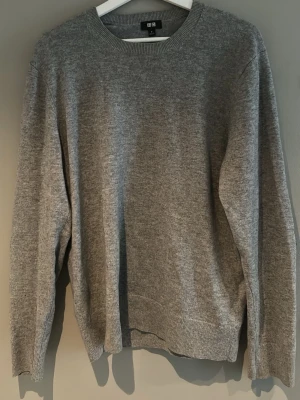 Grå stickad kashmir tröja från Uniqlo - Snygg grå stickad kashmir tröja från Uniqlo med rund halsringning och svarta armbågslappar.