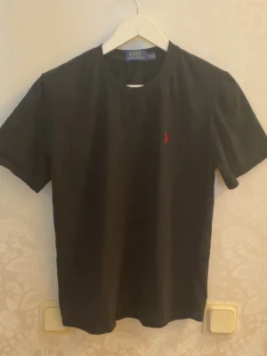 Svart t-shirt från Polo Ralph Lauren - Chill Polo Ralph Lauren tshirt, toppen skick i storlek S. Passar perfekt nu inför sena sommar kvällar. Tveka ej att höra av dig vid funderingar eller intresse! 🫡🔥