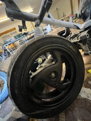 Svart bakhjul till moped - Säljer ett svart bakhjul till moped med aluminiumfälg och däck. Hjulet har tre ekrar och sitter monterat på en ram med stötdämpare. Passar till dig som bygger eller lagar moped.