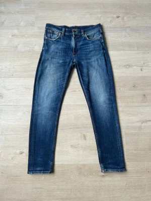 Blåa Nudie Jeans Slim Regular Fit Storlek W30 L32  - Mycket fina Diesel Jeans i blå färg. Jeansen är i mycket bra skick och sparsamt använda. |  Äkta som allt annat jag säljer! ✅ |  Storlek: W30 L32 | Skick: Mycket Bra Skick - blivit lagade och en liten slitning men inget man tänker på (SE SISTA 2 BILDER) | Färg: Blå | Märke: Nudie | Modell: Jeans |   Hör gärna av dig vid frågor så svarar jag så fort jag kan! 😁 |  (SKU - 114)