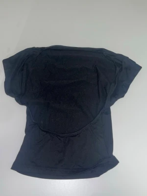 Svart basic t-shirt i bomull - En enkel svart t-shirt i mjuk bomull med korta ärmar och klassisk passform. Med öppen rygg, Perfekt att matcha med jeans eller shorts för en clean och stilren look.