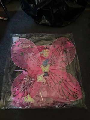 Fjäril kostym för barn - Säljer två maskeradkit med fjärilstema, 1 i rosa och 2 i lila. Seten innehåller stora vingar dekorerade med glitter och fjärilar, samt matchande diadem och trollstav. Perfekt för cosplay eller maskerad. Materialet är lätt mesh och plast.den rosa har även en kjol och det är anledningen varför den är dyrare Den rosa kostar 130kr Den lilla kostar 100kr 2 lila 160kr Alla 3 för 270