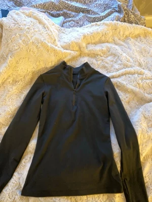 Svart tränings långärmad  med half zip - Svart långärmad med halv dragkedja framtill. Mjuk bomulls material med samtidigt lite tärnings material.