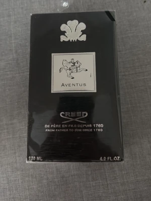 Creed Aventus Eau de Parfum 120ml - Helt oöppnad Lyxig parfym från Creed, Aventus, i en elegant svart och silverfärgad förpackning. Flaskan rymmer 120 ml och har en exklusiv design med en ryttare på etiketten. Perfekt för dig som gillar klassiska och sofistikerade dofter.