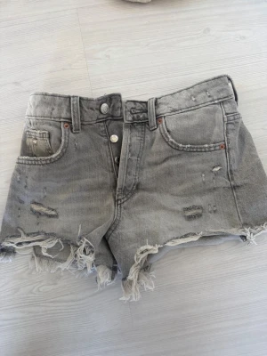 Grå  jeansshorts  - Grå jeansshorts från Zara med fransig kant och slitna detaljer. Jättebra skick, storlek 32💕