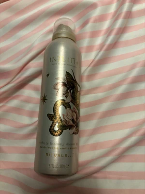 Rituals INUITA duschgelé 200 ml - Lyxig duschgelé från Rituals i serien INUITA med doft av sandelträ och vanilj. Flaskan är silverfärgad med dekorativt ormmotiv och blommor i guld och rosa. Innehåller 200 ml och har en praktisk sprayfunktion.
