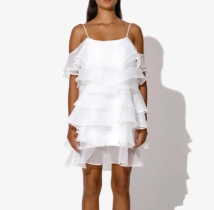 Vit volangklänning med tunna axelband - Superfin vit kortklänning med flera lager volanger och tunna axelband. Klänningen har en luftig och flowy känsla, perfekt för varma dagar. Tillverkad i ett lätt och skirt material som ger en romantisk look. Använd 1 gång! Ny pris: 2599kr. Skriv för mer frågor, skickar snabbt!
