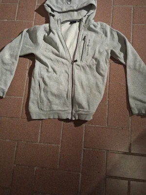 Grå sail-racing 160 men sitter som 155 - Grå sail-racing zip up tröja i storlek 160 men passar ungefär 155. Den är lite söndrig i slutet på ärmarna men annars är den i bra skick. Hör av dig om du har frågor eller om du vill diskutera priset.