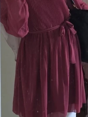 Rosa kortklänning med volangärm - Söt rosa kortklänning med plisserad överdel, volangärmar och knytskärp i midjan. Klänningen har en luftig känsla och är perfekt för varmare dagar. Den är ärmlös med transparenta detaljer och har en feminin siluett. Passar S/M