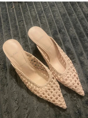 Beige flätade sandaler från Zara - Säljer ett par snygga beige sandaler från Zara med spetsig tå och öppen häl. Skorna har en flätad design i textilmaterial som ger en luftig känsla. Perfekta för sommarens alla outfits och lätta att bara kliva i.