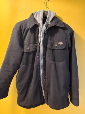 Svart overshirt från Dickies med huva - Stilren svart overshirt från Dickies med grå huva och dragkedja. 