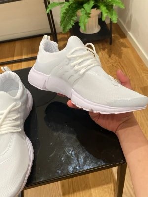 Nike Presto - Fräscha vita Nike Presto sneakers med mesh-ovandel och vita snören. Skorna har en clean design med diskreta swoosh-loggor och transparenta detaljer på sidorna. Perfekta för dig som gillar sportig och stilren look. Vid snabb affär kan priset diskuteras