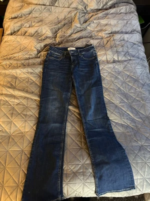 Blå bootcut jeans från Zara - Säljer ett par blå bootcut jeans från Zara i klassisk tvätt. Jeansen har fem fickor, normal midja och utsvängda ben. Tillverkade i ett mjukt denimtyg som ger en skön passform. Perfekta för dig som gillar retrovibbar och vill ha ett par jeans som sticker ut.