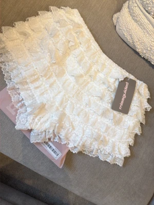 Nya i förpackning! Vita spetsvolangshorts från Missguided - Superfina vita shorts från Missguided med flera lager volanger i spets. De har en feminin och lekfull look med hög midja och är perfekta för varma dagar. Materialet är lätt och luftigt, vilket gör dem bekväma att bära.