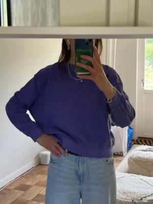 Lila sweatshirt i oversized modell - En enkel och snygg lila sweatshirt med avslappnad passform och rund hals. Tröjan har långa ärmar och ribbade muddar vid ärmslut och nederkant. Perfekt att matcha med jeans för en chill look.