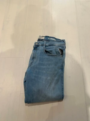 Ljusblå jeans från Replay W31 L34 - Snygga ljusblå jeans från Replay med klassisk femficksdesign och raka ben. Jeansen har en stilren look med diskreta detaljer och är tillverkade i mjukt denimtyg som ger en skön passform. Helt nya och bara använda en enstaka gång vilket man ser på lappen på insidan. Kvitto och allt sånt finns. Köpta på NK. Hör av er vid frågor. MVH Viggo