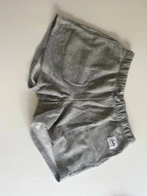 Grå mjukisshorts från Andy - Mysiga grå mjukisshorts från Andy med elastisk midja och kort passform. Perfekta för chill dagar eller träning. Tillverkade i mjukt bomullsmaterial för maximal komfort.
