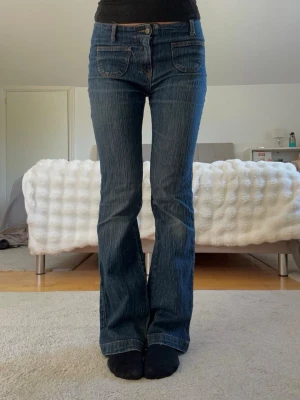 Low waist bootcut jeans - Säljer dessa Brandy Melville jeans i lågmidjat med dekorativa fickor där fram, lite slitna i botten annars i bra skick. Original pris 599kr säljer för 175kr. Är 169cm lång och storlek S!