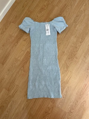 Ljusblå smock klänning puffärmar - Ljusblå klänning med smockad kropp. Aldrig använd