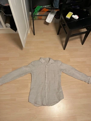 Zara  linneskjorta - Snygg beige skjorta i linne med klassisk krage och knäppning framtill. Skjortan har lång ärm och en avslappnad passform som passar perfekt till både jeans och chinos. Enkel och stilren design utan mönster eller extra detaljer.