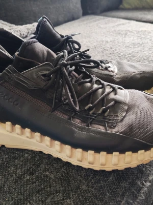 Svarta ECCO sneakers med chunky sula - Säljer ett par svarta ECCO sneakers med cool chunky vit sula och snörning. Skorna har en mix av mesh och lädermaterial som ger en modern look. Perfekt för dig som gillar streetstyle och komfort. ECCO-loggan syns på sidan.