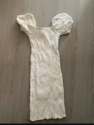 Vit klänning med puffärmar Gina Tricot - Supersöt vit klänning från Gina Tricot med smockad kropp och stora puffärmar. Klänningen har en tight passform och är tillverkad i ett mjukt bomullstyg. Perfekt för dig som vill sticka ut med en trendig och feminin look.