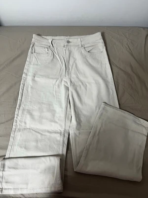 Beiga raka jeans med fem fickor - Snygga beiga jeans med rak passform och klassisk femficksdesign. Jeansen har normal midja och stängs med dragkedja och knapp. Perfekta för en clean och stilren look. Materialet är denim i bomull.