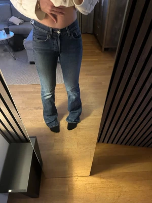 Blå bootcut jeans från Levi's - Säljer ett par klassiska blå bootcut jeans från Levi's med fem fickor och normalhög midja. Jeansen har en snygg tvättad look och är tillverkade i denim med lätt stretch. Passar perfekt till en avslappnad stil och är riktigt bekväma. Är osäker på storlek men skulle gissa s xs 34 i lång typ