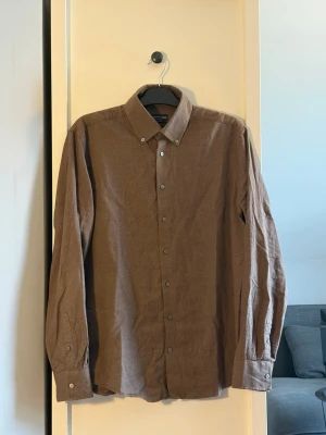 Brun bomullsskjorta från Bruun & Stengade - Stilren brun skjorta i linne från Bruun & Stengade. Klassisk krage och långa ärmar. Perfekt för en avslappnad men snygg look. Nypris 999kr.