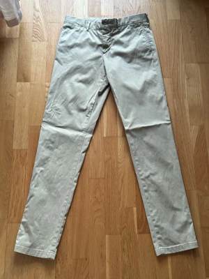 J.Lindeberg Chinos - J.Lindeberg chinos i ljusbeige färg. Stilrena och lättmatchade byxor med clean passform, perfekta till vardags eller mer dressade outfits. 30x34