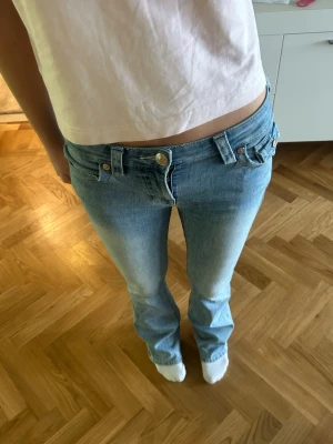 Ljusblå bootcut jeans från True Religion - Säljer ett par jätte fina ljusblå bootcut jeans från True Religion med låg midja och snygga detaljer.  36 cm tvärs över midjan och passar mig som är 170cm