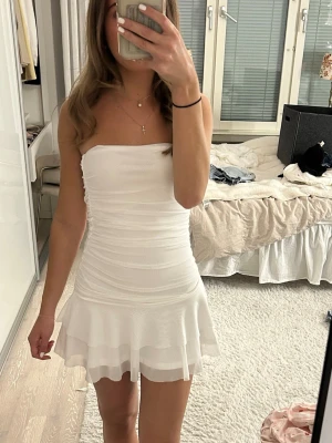 Vit offshoulder klänning - Säljer en söt vit offshoulder kort klänning med figurnära passform och volang nertill. Saknar lapp då den är köpt begagnat