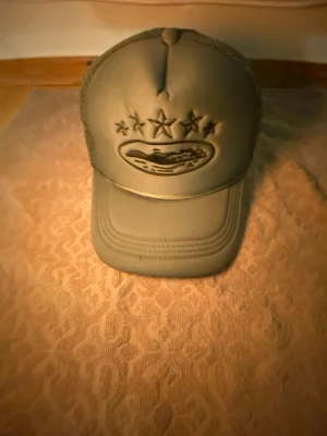 Grå truckerkeps med mesh - Snygg grå truckerkeps med böjd skärm och mesh på sidorna för extra ventilation. Kepsen har broderad logga framtill och justerbar snapback baktill. Perfekt för en avslappnad streetstyle-look.