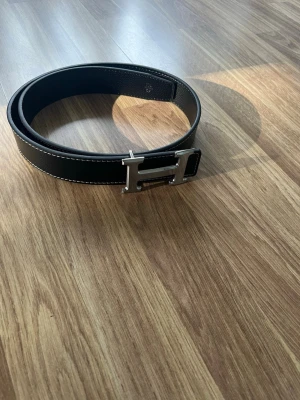Svart H bälte - Du får ett svart läder bälte med ett H på. Den är 105cm lång. Passar till de mesta outfitsen. Pris går att diskuteras vid snabb affär! Jag skickar snabbt, inom 24h!