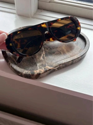 Coola solglasögon  - Snygga solglasögon med bred båge i klassiskt sköldpaddsmönster. Glasen är mörka och bågarna har en cool, retroinspirerad form. Perfekta för att lyfta din stil under soliga dagar.