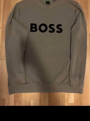Äkta olivgrön sweatshirt från BOSS - Orginal olivgrön sweatshirt från BOSS med svart logotyp framtill. Perfekt för en avslappnad och trendig stil. Pris kan diskuteras i DM.