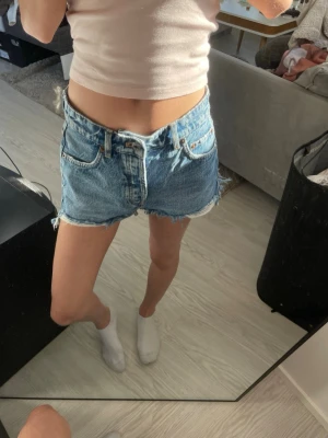Blå jeansshorts - Säljer ett par klassiska blå denimshorts med fransig kant och femficksmodell. Shortsen har låg midja💕