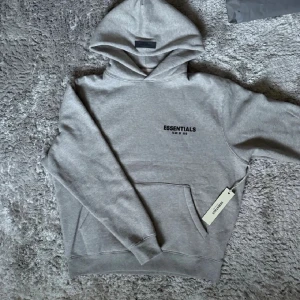 Fear of God hoodie - Hej! Säljer denna essentials fear of God hoodie som är sjukt snygg och skön för en chill vibe, Storlek: XS men passar mer för dem som har S. Den är rätt stor i passform. Endast prövad en gång och tvättas såklart innan frakt! Den är självklart äkta! ✅ Nypris: ≈ 1200kr | vårt pris: 599kr! Vilket är en sjukt bra deal! Färg: Grå 🩶. Tags och påse följer med via köp, fler frågor? Kontakta mig! 👀💬 