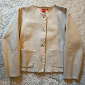 Beige cardigan jacka från RYVLS - Superfin beige cardigan jacka från RYLS med snygga dekorativa sömmar längs kanterna, stora knappar framtill och två praktiska fickor🥰.