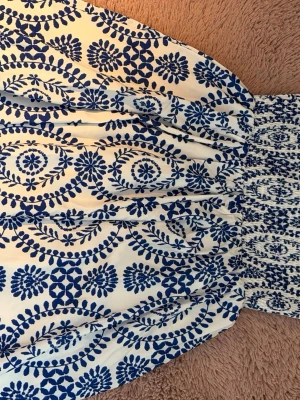 Vit och blå mönstrad långkjol - Superfin vit långkjol med blått blommigt mönster och smock i midjan. Kjolen har en luftig och flowy känsla, perfekt för varma dagar. Materialet känns lätt och bekvämt mot huden.NY UTAN PRISLAPP ‼️ köpte för 440kr och säljs även inte längre i butik så passa på att köpa för ett bra pris. Passar från xxs-m